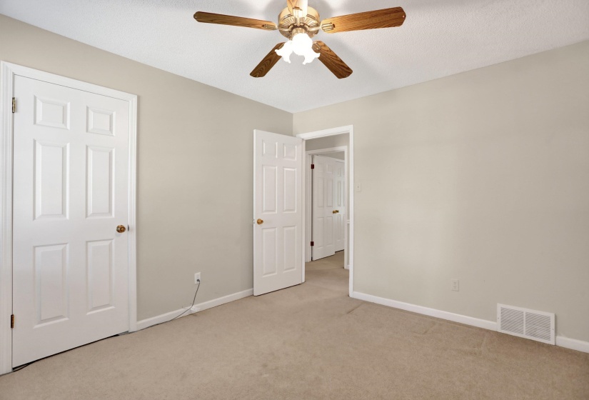 Neutral tone wall paint with white trim, a ceiling fan with wooden blades, and carpet flooring