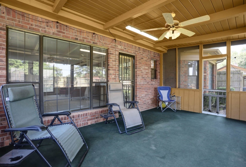 Screened porch featuring a painted concrete floor, brick wall, wood-paneled ceiling, and a ceiling fan with integrated lighting