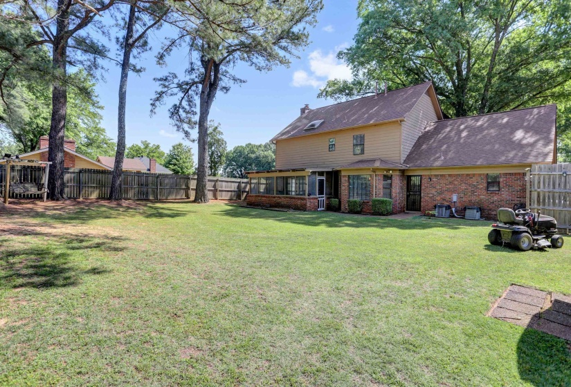 Spacious rear yard with established trees, wood fencing, and a two-story exterior featuring brick and siding