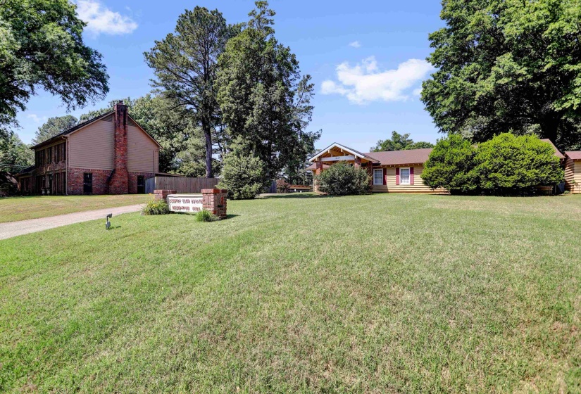 Manicured lawn with a long driveway leading to two distinct structures