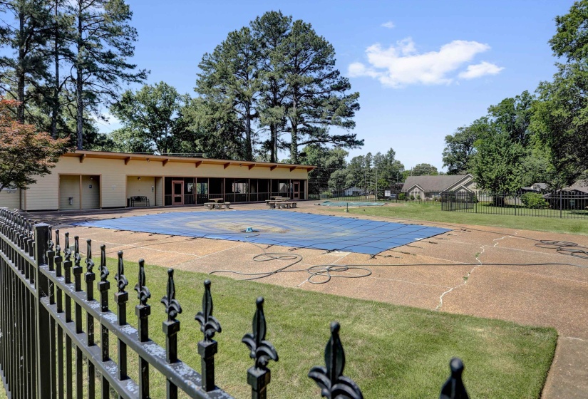 Outdoor pool area featuring a large covered pool, extensive surrounding patio, and a dedicated pool house with multiple windows