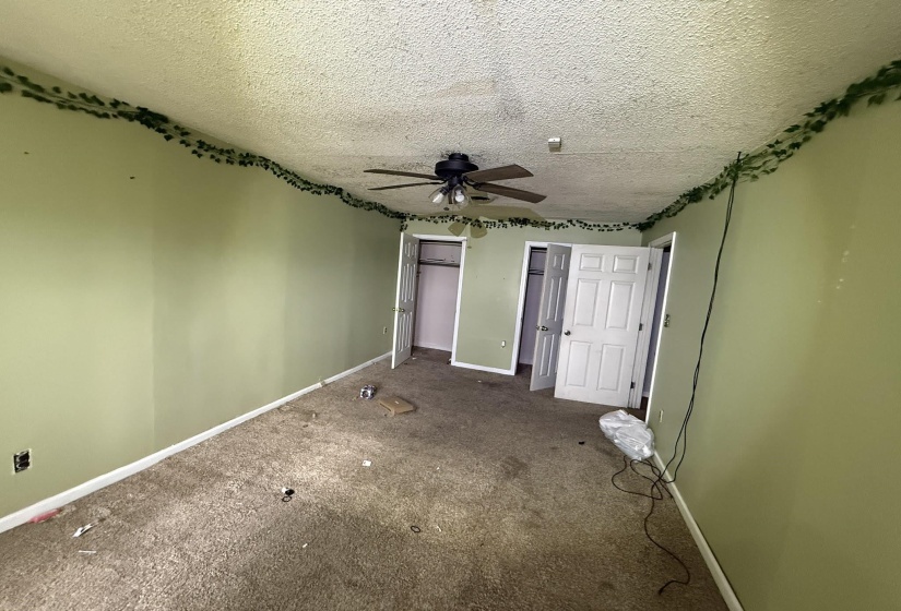 Room featuring textured ceiling, carpeted flooring, and a ceiling fan with light fixture