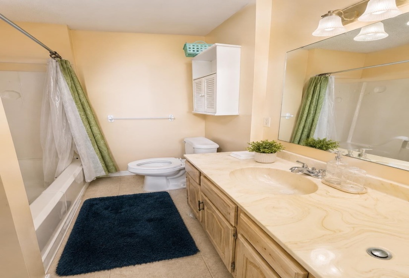 Bathroom featuring a built-in vanity with wood-finish cabinetry, an integrated sink, and an expansive mirrorAI-Enhanced Photo — May Not Reflect Exact Current Condition