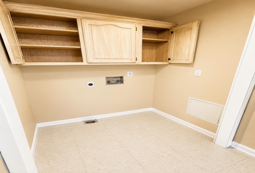 Utility space featuring wood-finish upper cabinetry with interior shelving, square tile flooring, and light-toned wall paint AI-Enhanced Photo — May Not Reflect Exact Current Condition