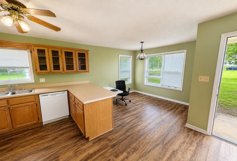 Kitchen featuring wood-finish flooring, light wood cabinetry, and a double basin stainless steel sink AI-Enhanced Photo — May Not Reflect Exact Current Condition
