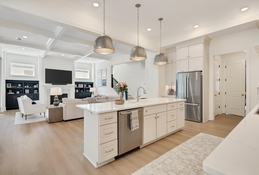 Gourmet kitchen with white cabinetry, stainless steel appliances, and a central island featuring a sink and pendant lighting