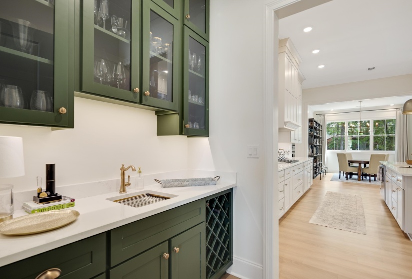 Custom cabinetry in an olive tone, featuring glass-front upper cabinets with integrated lighting