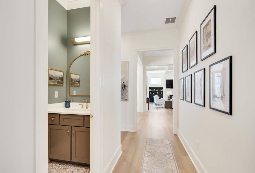 Hallway featuring light wood-finish flooring, white walls, and a recessed ceiling vent