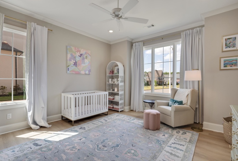 Spacious room featuring wood-finish flooring, two large windows with white trim, and a ceiling fan with integrated lighting