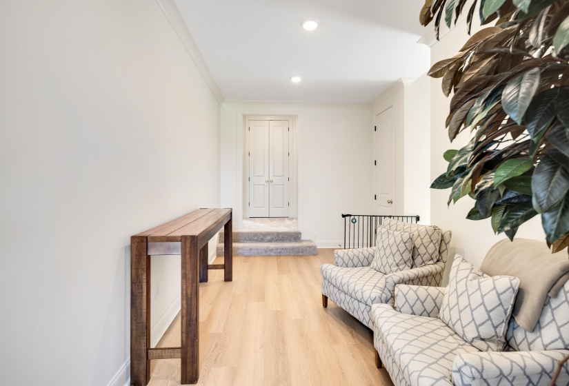 Light wood-finish flooring extending into a carpeted landing