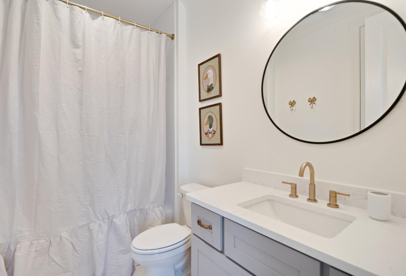 Bathroom featuring a white toilet, light gray vanity with white countertop, integrated sink, and gold-finish fixtures