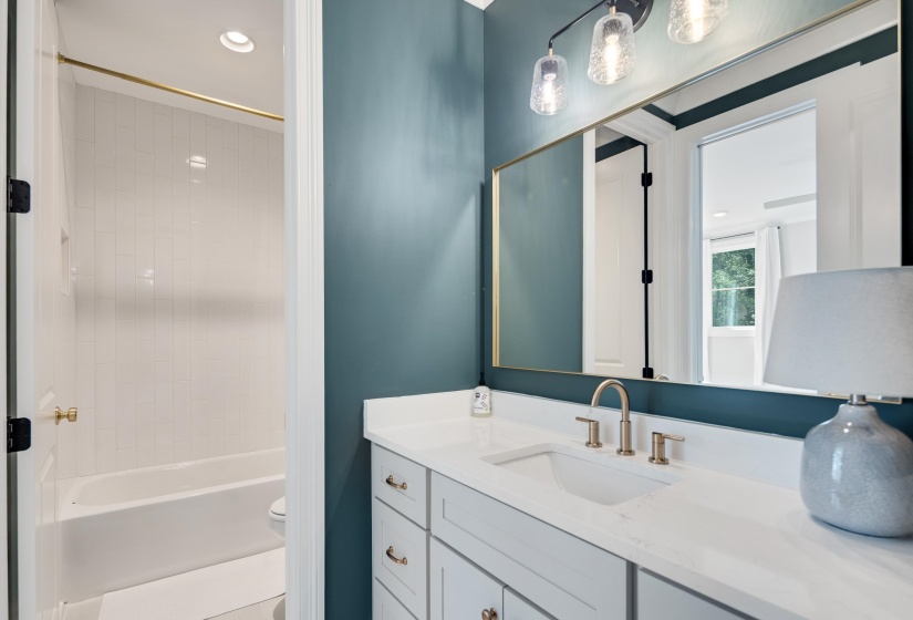 Bathroom vanity featuring a single basin, brushed gold faucet, and a large mirror with a gold frame