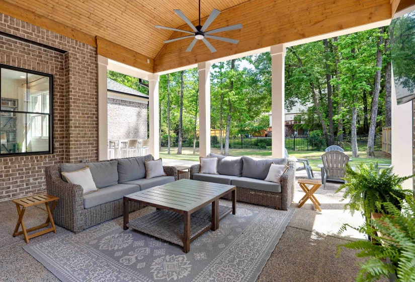 Covered outdoor patio featuring brick siding and a natural wood-finish ceiling with a ceiling fan
