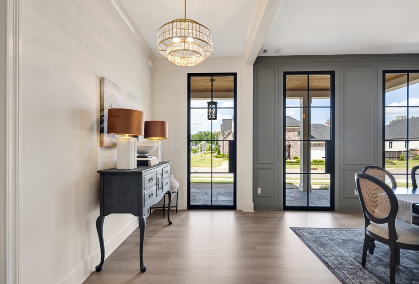 Interior space featuring wood-finish flooring, a tiered crystal chandelier, and paneled walls