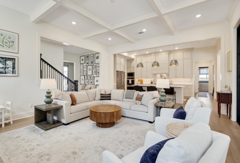 Open-concept living space featuring wood-finish flooring and a coffered ceiling with recessed lighting
