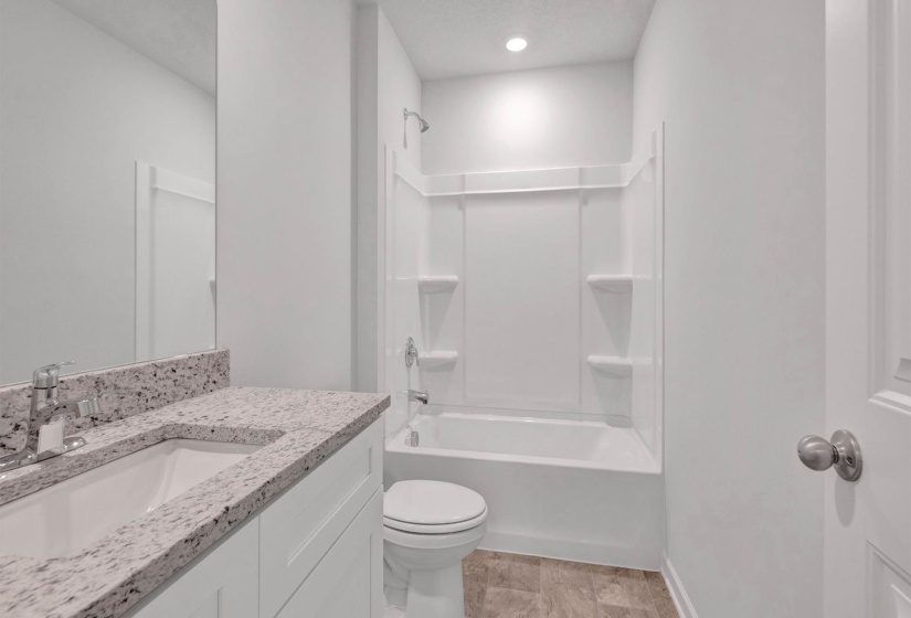 Bathroom featuring a white vanity with a speckled countertop, undermount sink, and chrome faucet