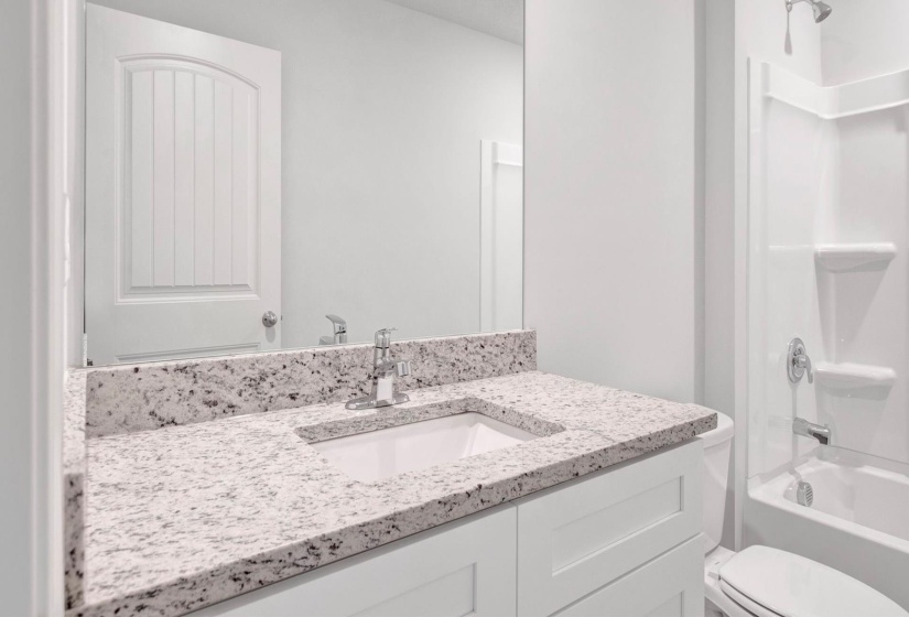 Bathroom vanity featuring a speckled countertop, undermount sink, and chrome faucet