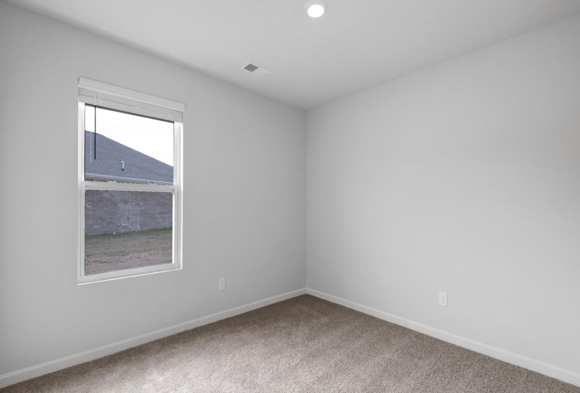 Neutral-toned carpeting complements light-colored walls in this room, featuring a white-framed window with blinds