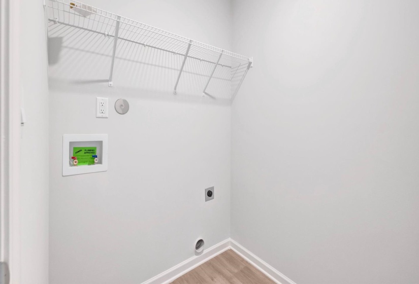Dedicated laundry area featuring a wire storage shelf, utility hookups, and wood-finish flooring