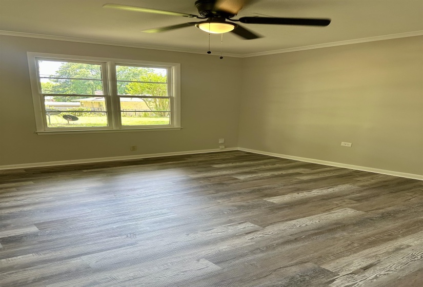 Spacious room with wood-finish flooring, neutral-toned walls, and a ceiling fan with integrated lighting