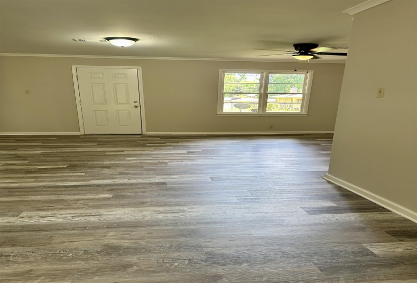 Spacious room featuring wood-finish flooring, neutral-toned walls, and white baseboards