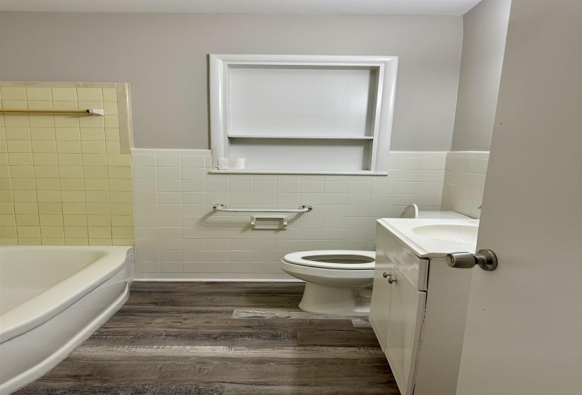 Bathroom featuring wood-finish flooring, a white porcelain toilet, and a white vanity with an integrated sink