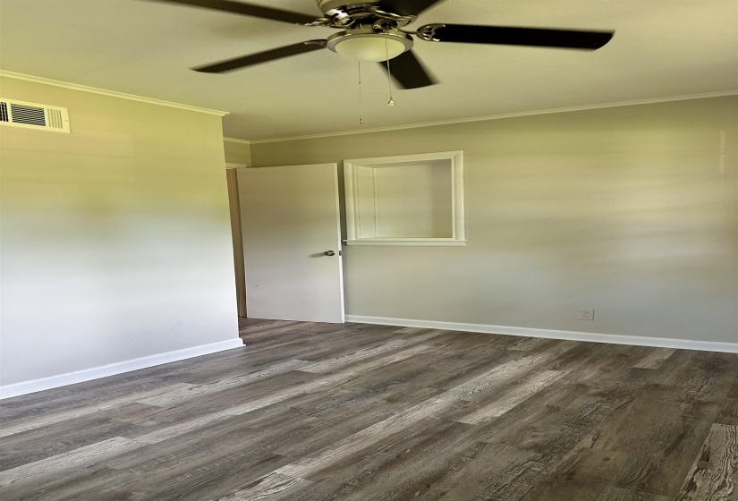 Interior room featuring wood-finish flooring, light-toned wall paint, a ceiling fan with integrated lighting, white trim, and a wall niche