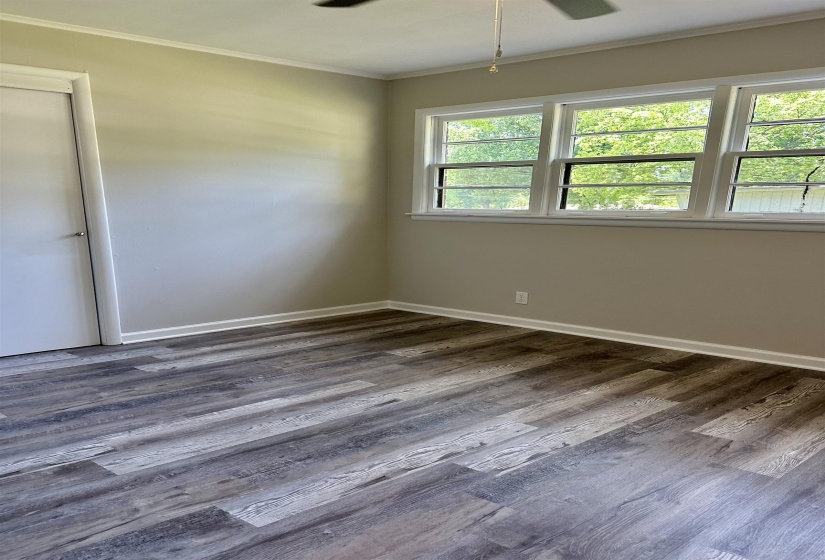 Spacious room featuring wood-finish flooring, light-toned walls, white trim, and a ceiling fan