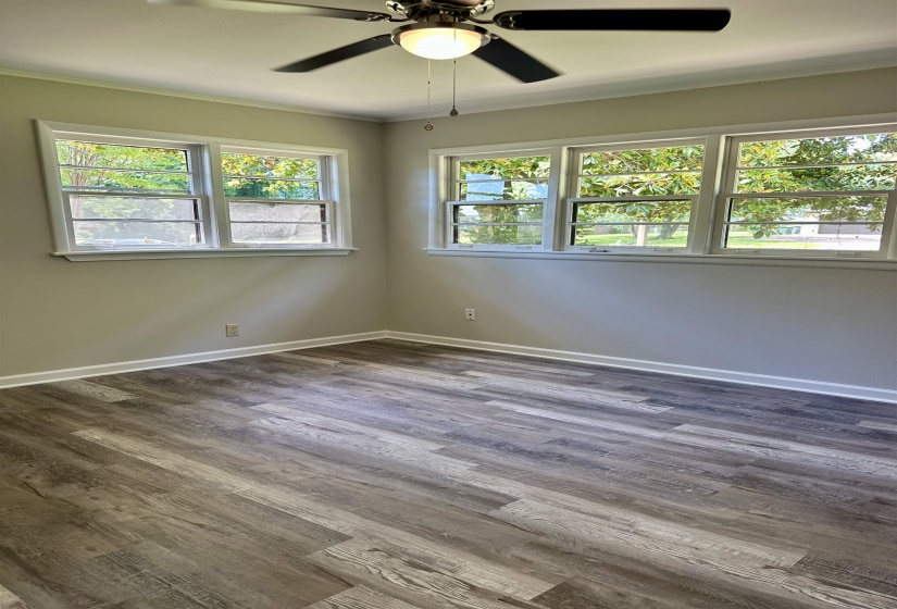 Spacious interior featuring wood-finish flooring, light grey wall paint, and multiple windows with white trim