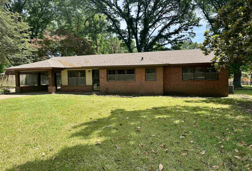 Brick exterior residence featuring a carport, multiple windows, and a shingle roof