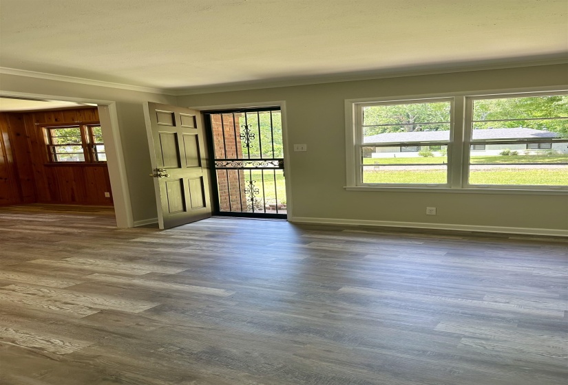 Spacious room with wood-finish flooring, light neutral wall paint, and a white crown molding trim