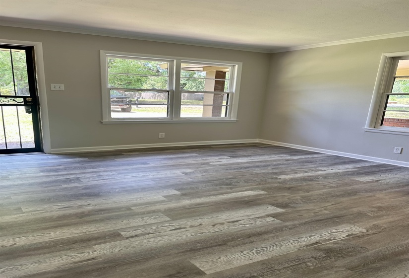 Living area featuring wood-finish flooring, light neutral wall tones, white baseboards, and white window trim