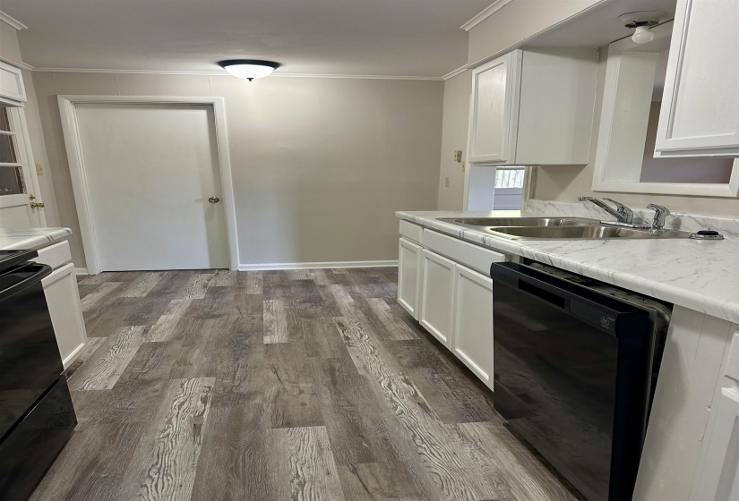 Kitchen featuring wood-finish flooring, white cabinetry, a dual basin stainless steel sink, and a black built-in dishwasher