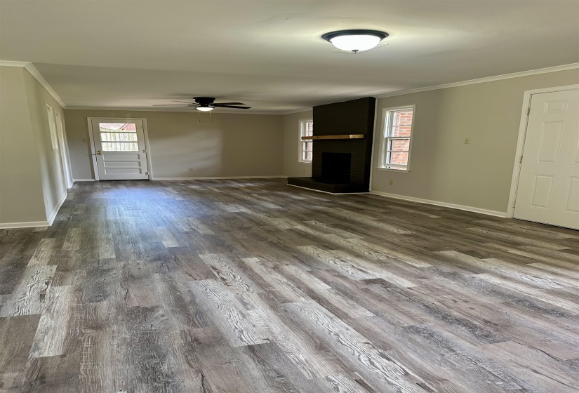 Spacious interior featuring wood-finish flooring, a contemporary fireplace with a wood mantle, ceiling fan, and white trim