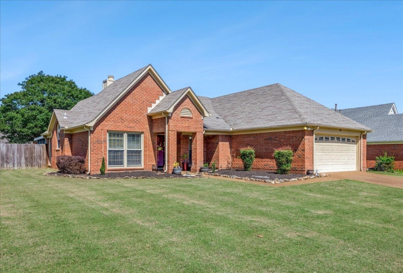 Brick exterior residence with an attached garage, featuring a gabled entryway and a shingled roof