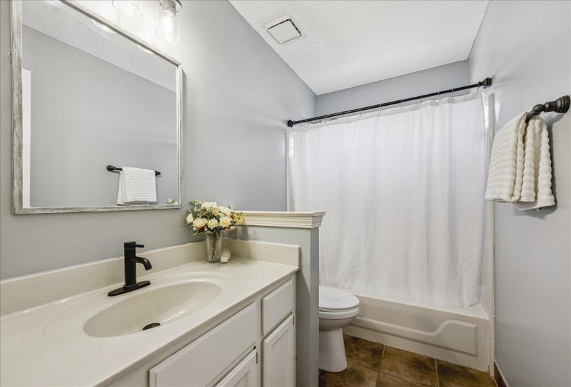 Bathroom featuring a white vanity with integrated sink, black-finish faucet, and a framed mirror