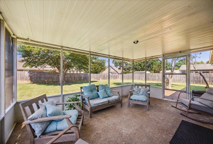 Screened-in porch featuring a textured concrete floor, beadboard ceiling, and a full-view screen door leading to the backyard