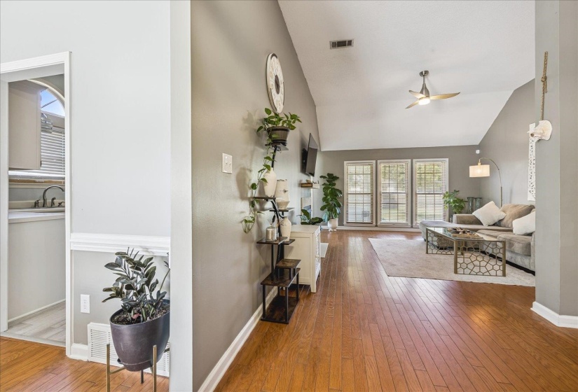 Spacious living area featuring wood-finish flooring, vaulted ceilings, and a ceiling fan