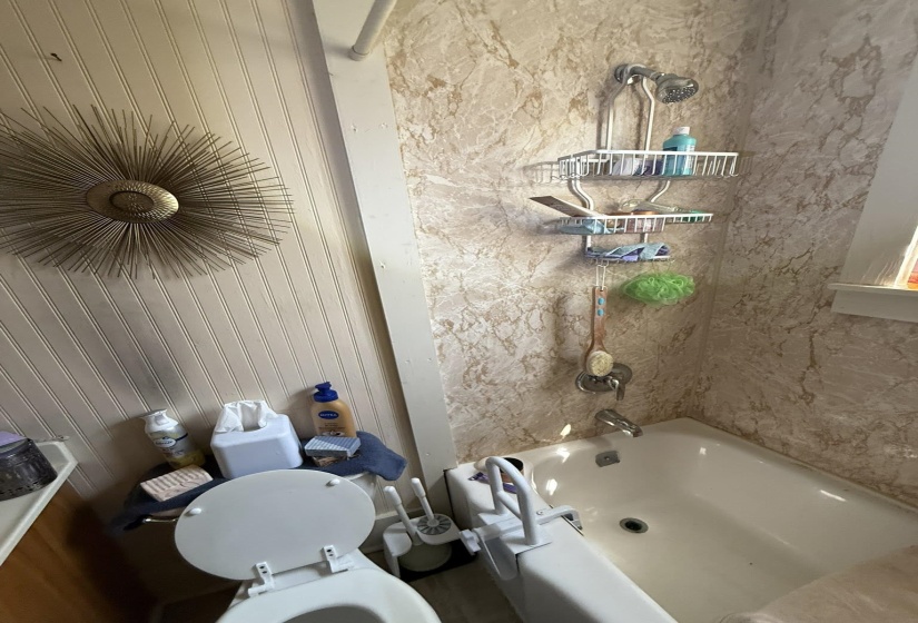 Full bathtub with a built-in shower featuring a chrome fixture and patterned shower surround