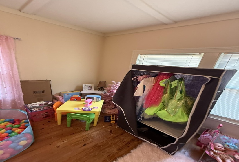 Room featuring wood-finish flooring, light-toned walls, and crown molding