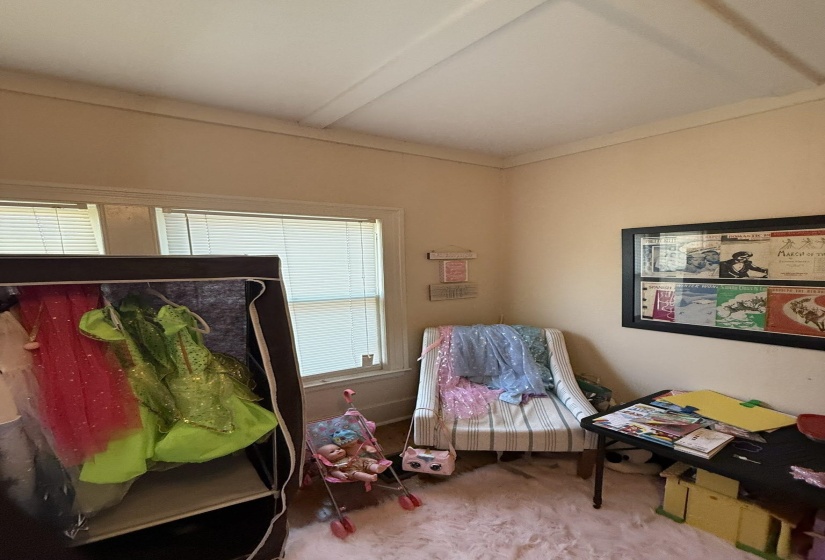 Room featuring a single window with horizontal blinds, light-toned walls, and crown molding