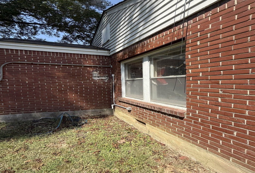 Red brick exterior with white trim, featuring a double-hung window and horizontal vinyl siding