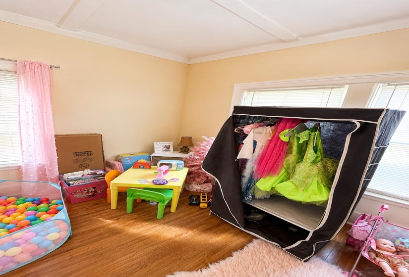 Room featuring wood-finish flooring, light-colored walls, and a tray ceiling with crown molding