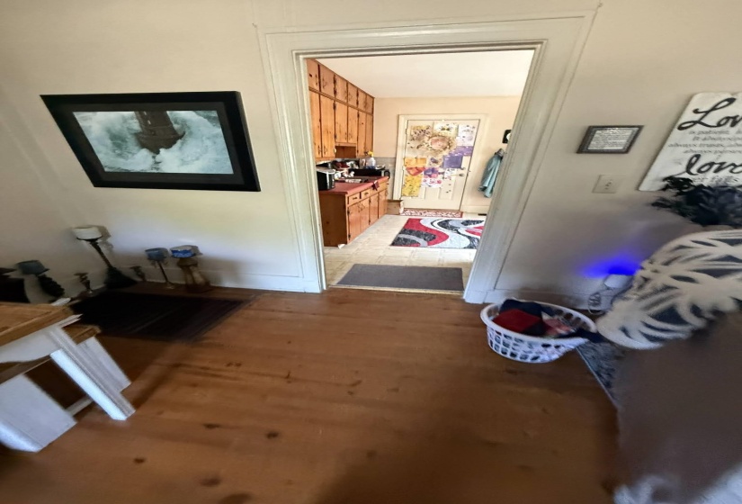 Hardwood flooring extending into a doorway with white trim