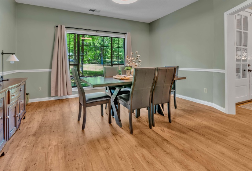 Windowed room featuring light wood-finish flooring, two-tone wall paint, white chair rail molding, and a large window with grilles