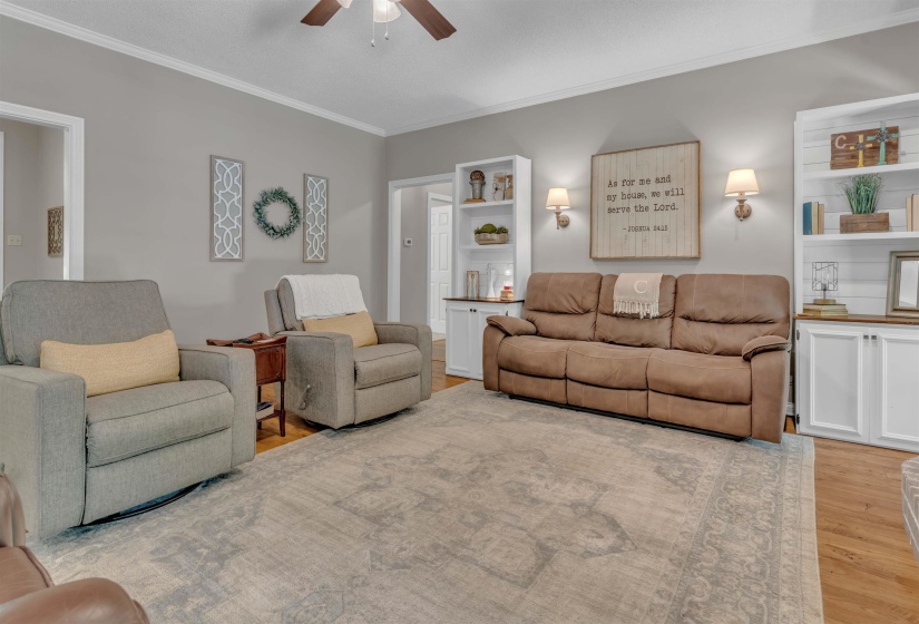 Living area featuring wood-finish flooring, light gray wall tones, and white crown molding