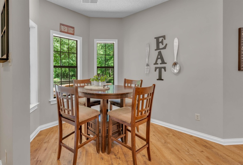 Bay window dining area featuring wood-finish flooring, light gray wall paint, and white trim