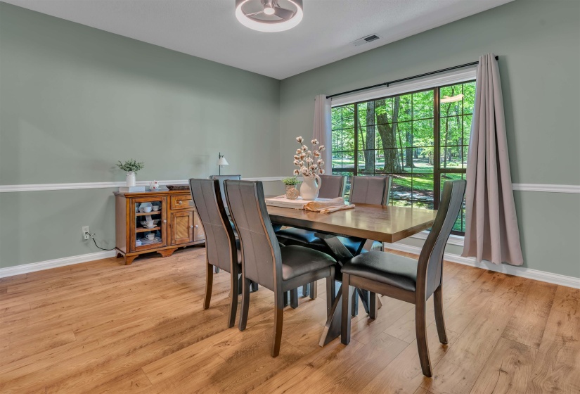 Formal dining space featuring wood-finish flooring, a contemporary ceiling light fixture, and an expansive window with black grid panes