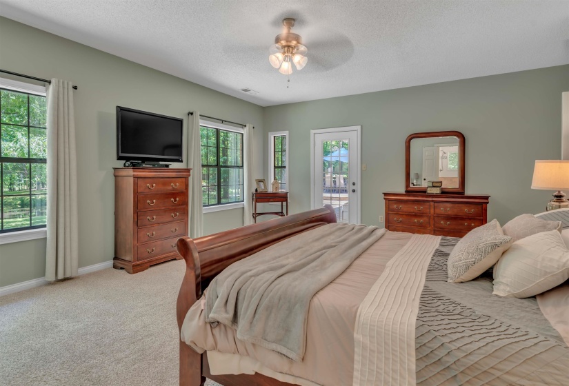 Spacious room featuring light green walls, neutral carpet flooring, and a ceiling fan with integrated lighting