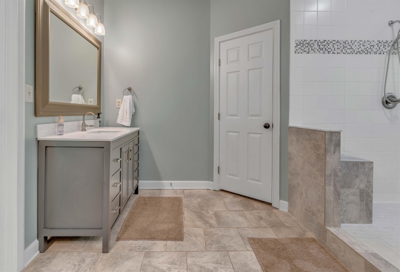 Bathroom featuring a gray vanity with an integrated sink, framed mirror, and five-panel interior door